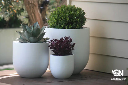 Collection of classic terracotta and ceramic plant pots in various sizes displayed on garden bench