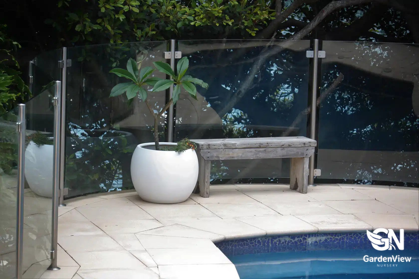 Curved dome-shaped ceramic pots in various sizes displaying different plants on a garden bench